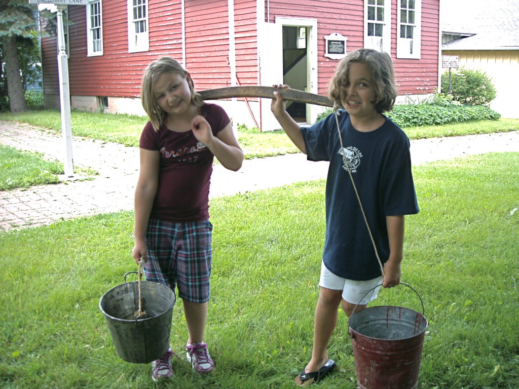 two children carrying buckets