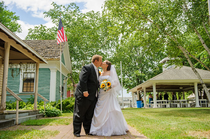 Bride and groom kissing with historic wedding venue in the background